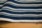 Close-up of vintage hand-woven indigo blue striped cotton textile, showing edge detail.