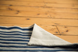 Folded vintage African indigo striped textile revealing natural cotton reverse.