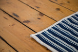 Vintage hand woven indigo striped cotton textile corner, finished with cream binding.