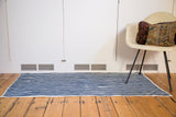 Hand-woven African indigo textile, showing irregular blue and natural striped pattern.