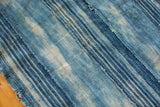 Vintage African indigo textile close-up, highlighting handwoven texture and unique faded blue stripes.
