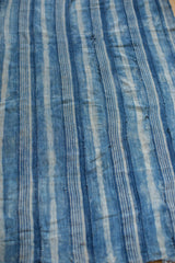 Handwoven vintage indigo textile showing variegated blue and off-white stripes.