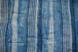 Intricate hand-woven texture and varied indigo blue stripes of the vintage textile.