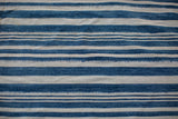 Subtle variations in hand-woven indigo blue and natural striped cotton textile.