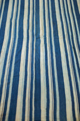 Visible texture of the hand-dyed indigo textile, featuring varied blue and white stripes.