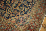 Angled corner view of vintage Heriz rug showcasing distressed herati pattern and bold navy ground.