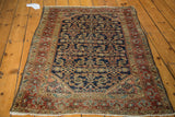 Distressed navy Herati pattern and red-toned border on a vintage Heriz rug corner.