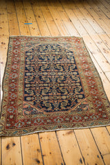 Vintage Heriz rug corner with red border, navy Herati pattern, and worn fringe.