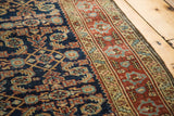 Detailed vintage Heriz rug: worn navy ground, intricate herati design, and terracotta border.
