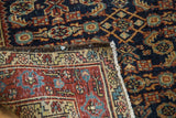 Vintage Heriz rug's folded corner reveals bold navy Herati pattern and secured edge.