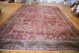 Distressed pile of the antique Mahal rug, showing rusty orange field, dark blue border, and fringe.