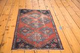 Corner of antique Mehrevan rug; geometric palmette pattern in distressed burgundy and sky blue.