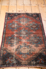 Distressed pile of antique Mehrevan rug, showing geometric palmette patterns in burgundy and sky blue.