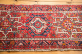Red, ivory, and blue geometric patterns on a vintage Karaja rug with a secured edge.