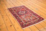 Corner view of a vintage Karaja rug with red, blue, ivory geometric patterns and white fringe.