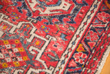 Hand-knotted red, ivory, and blue geometric motifs on a vintage Karaja rug.