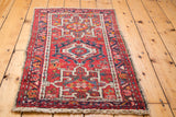 Karaja rug corner with geometric patterns in red, ivory, and blue, and visible fringe.