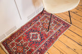 Corner detail of vintage Karaja rug with red, ivory, blue geometric pattern and fringed end.