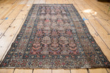Secured end of a 1930s vintage Kurdish rug, displaying repeating boteh and earthy tones.