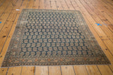 Antique Tabriz rug corner with repeating beige boteh, dusty charcoal field, and ornate border patina.