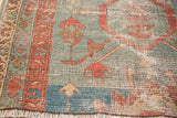 Antique Serapi rug's geometric terra cotta border and ivory fringe against an aqua blue field.