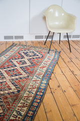 Distressed geometric Caucasian patterns and vibrant blue and red border on an antique runner.