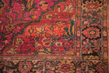 Persian Farahan Sarouk rug corner with ruby magenta, orange, and charcoal floral patterns.
