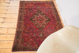 Intricate floral border and ruby magenta field pattern on a vintage Farahan Sarouk rug.