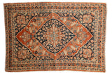 Antique Persian Tabriz rug with a contrasting deep navy floral medallion on a pale rusty orange field.