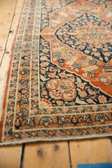 The intricate floral border of an antique Tabriz rug in contrasting rusty orange and deep navy.