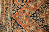 Intricate floral motifs on the navy and rusty orange border of an antique Tabriz rug.