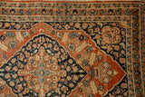 Intricate floral borders and navy spandrel on a rusty orange antique Persian Tabriz rug.