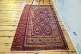 Antique Turkmen Chuval rug's intricate cranberry red, blue, and sand medallions and borders.
