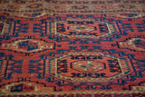 Softened cranberry and deep blue geometric medallions on an antique Turkmen Chuval rug.