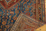 Shiraz rug's folded corner, displaying vivid sky blue field with pinwheels, pomegranates, and characterful patina.