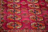Detail of vintage Bokhara Turkmen rug, vibrant magenta field, geometric guls, textural nuances.