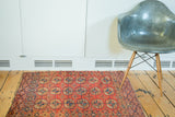 Antique Turkmen rug featuring repeating elephant footprint design in oxidized cranberry and navy blue.