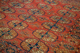 Detailed view of antique Turkmen rug's ornate elephant footprint guls in cranberry, teal, and ivory.