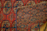 Antique Turkmen rug's cranberry pile, folded to reveal intricate foundation weave and blue selvage.