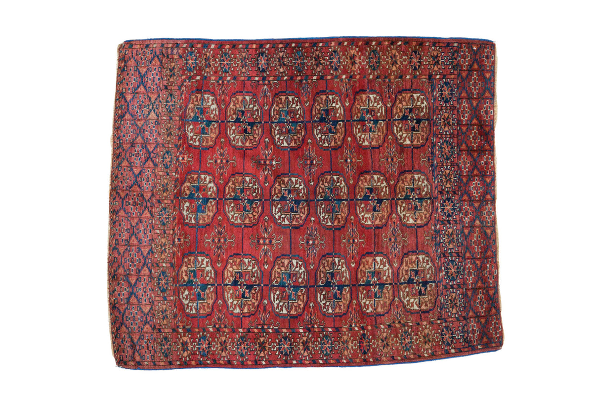 Antique Turkmen square rug with repeating elephant footprint design in oxidized cranberry red, teal blue.