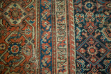 Distressed madder red geometric border and indigo field patterns of an Antique Fereghan carpet.