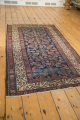 Corner of antique Hamadan Persian rug: indigo Herati field, antique ivory Serbend border, and fringe.