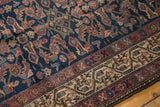 Close-up of antique Hamadan rug showing indigo field with Herati motifs and ivory Serbend border.