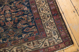 Corner of an antique Hamadan rug, showing Serbend border with geometric motifs in plum, indigo, and ivory.