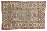 Antique Kazak rug displaying a rare light green field, wide geometric borders, and distressed character 4'2