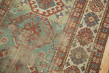 Distressed light green field and exposed foundation of an Antique Kazak rug.