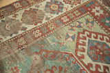Distressed antique Kazak rug, featuring rare light green field and wide geometric border.