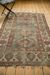 Distressed antique Kazak rug's rare light green field and wide geometric borders.