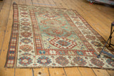 Collector Antique Kazak rug with a distressed light green field, wide borders, and geometric motifs.