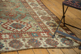 Worn antique Caucasian Kazak rug showing wide geometric borders and mellow green field.